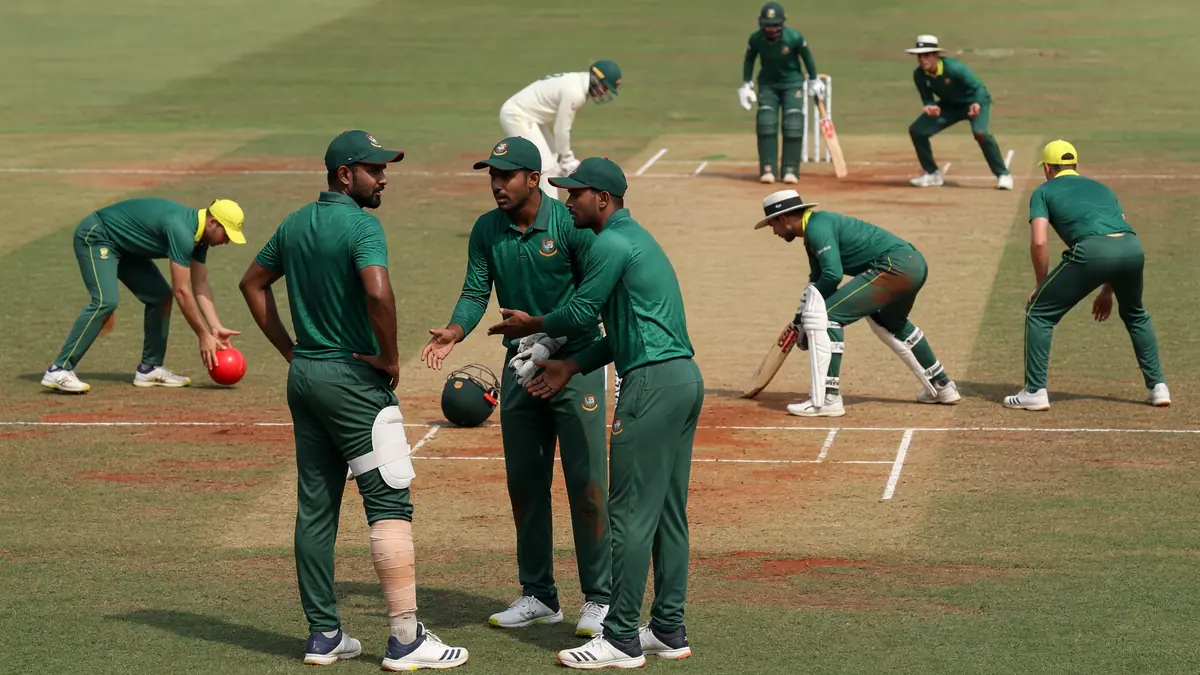 Medium view of fielders and bowler setting a Test-match field with batters at the crease under natural light